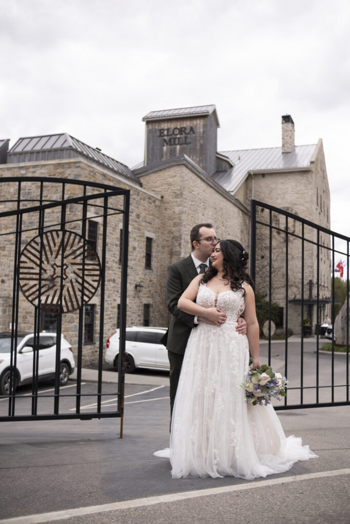 The bride sand groom embrace at the date of the Elora Mill, on their wedding day in Elora Ontario.