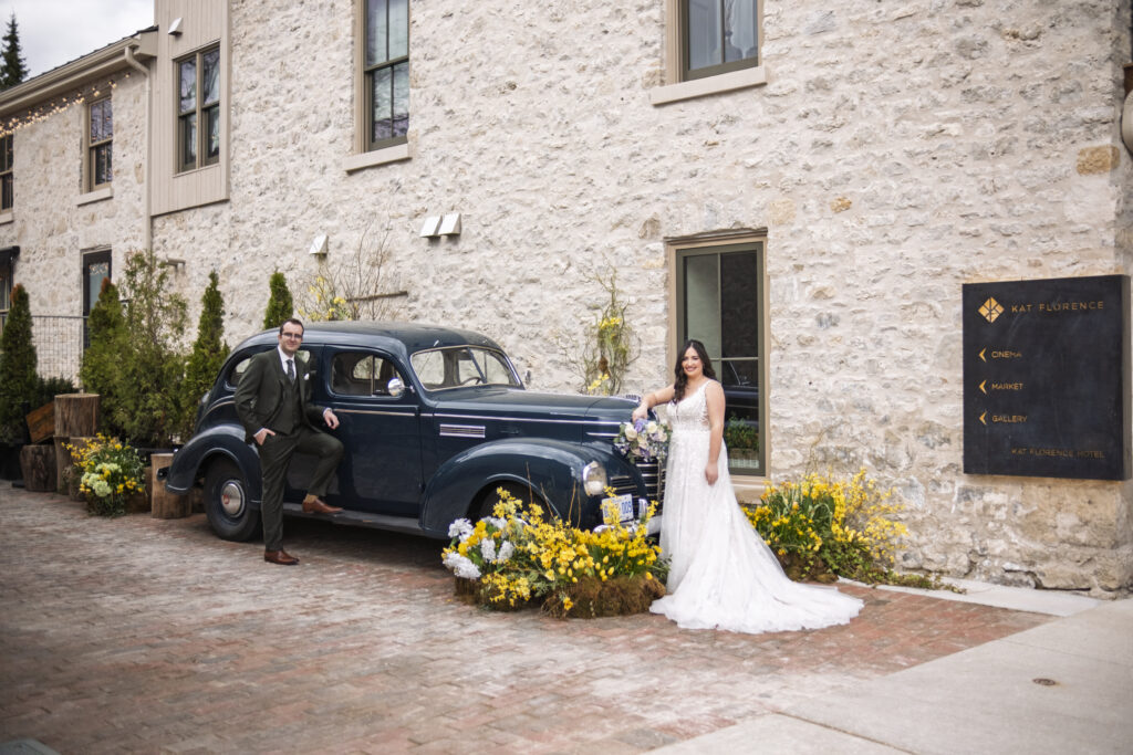 The Bride and groom pose next to an antique car down the road from the Elora Mill in Elora, Ontario. 