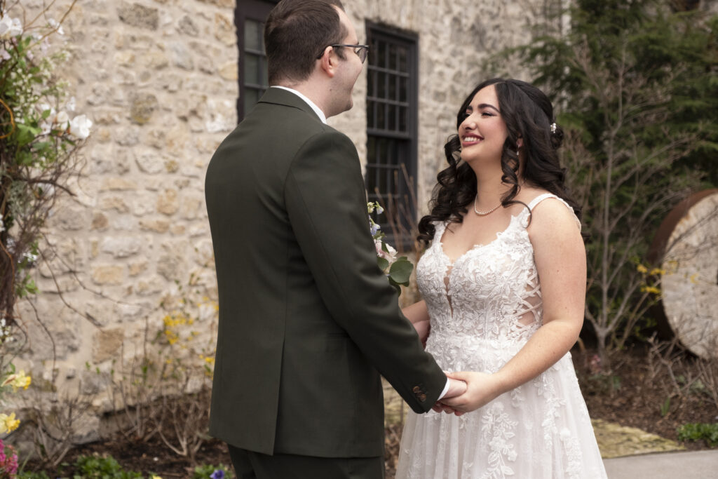 The bride and groom smile during their first look on their wedding day at the Elora Mill, in Elora Ontario.
