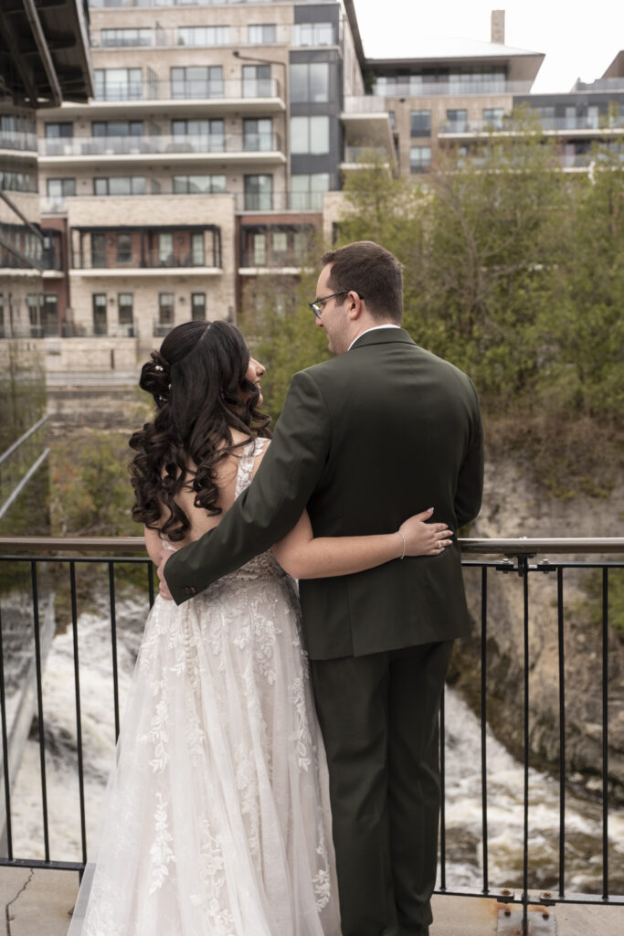 The bride and groom embrace while overlooking the Elora rapids at the Elora Mill, in Elora, Ontario. 