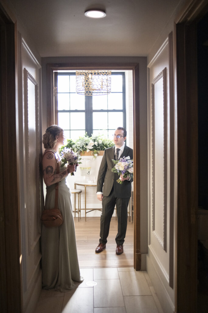 The groom chatting with a bridesmaid in the waiting suite at the Elora Mill Foundry Chapel, in Elora, Ontario. 