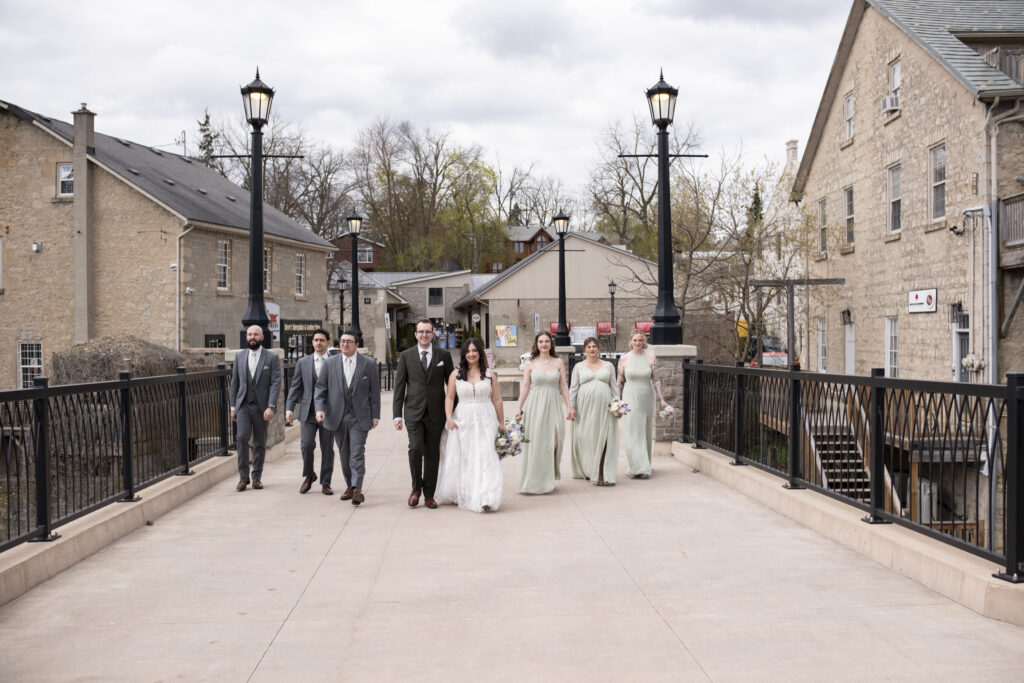 A wedding party walks across the bridge in an Elora Mill wedding in Elora, Ontario.