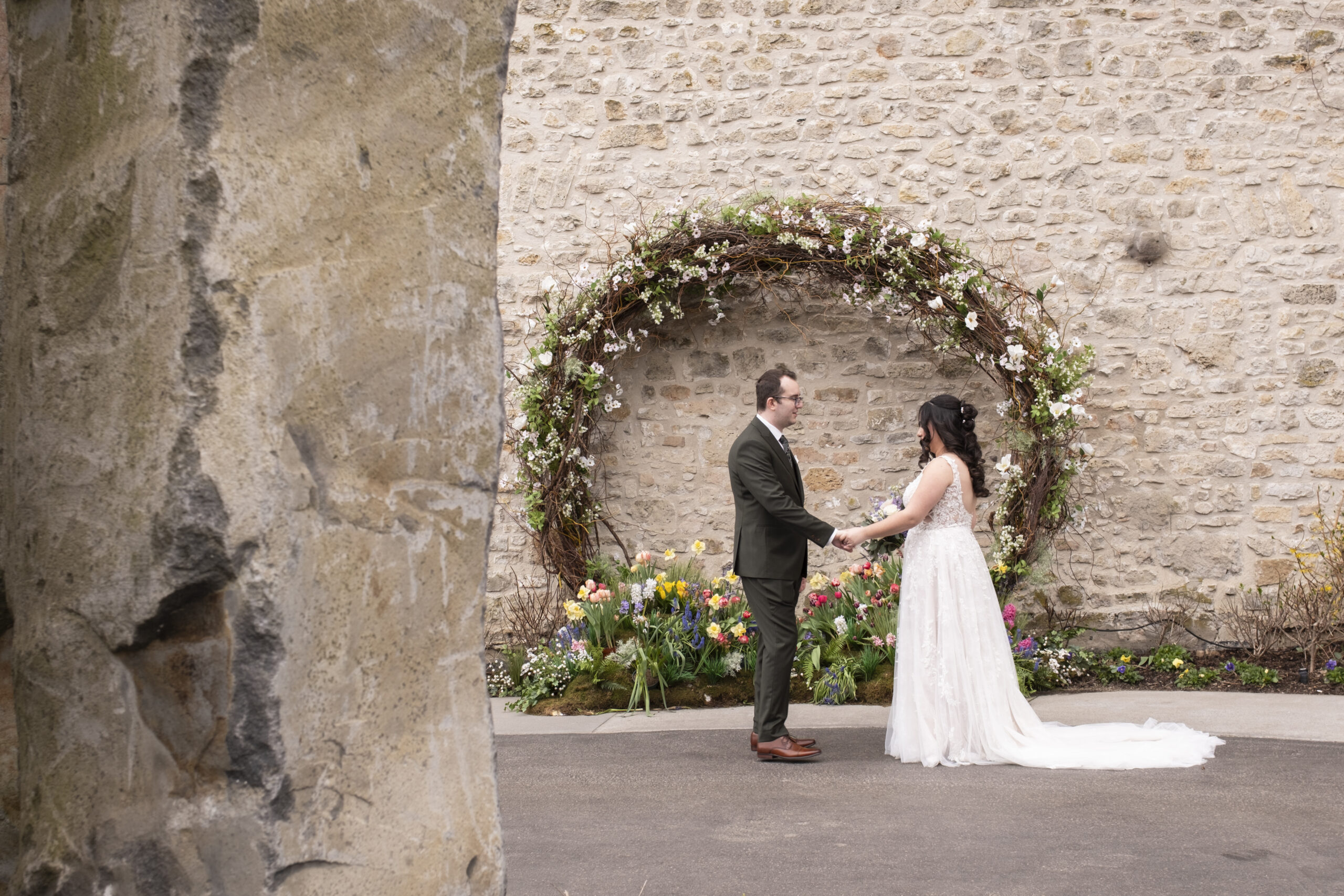 A wedding couple sharing their first look beneath a floral arch during an Elora Mill wedding in Elora, Ontario.