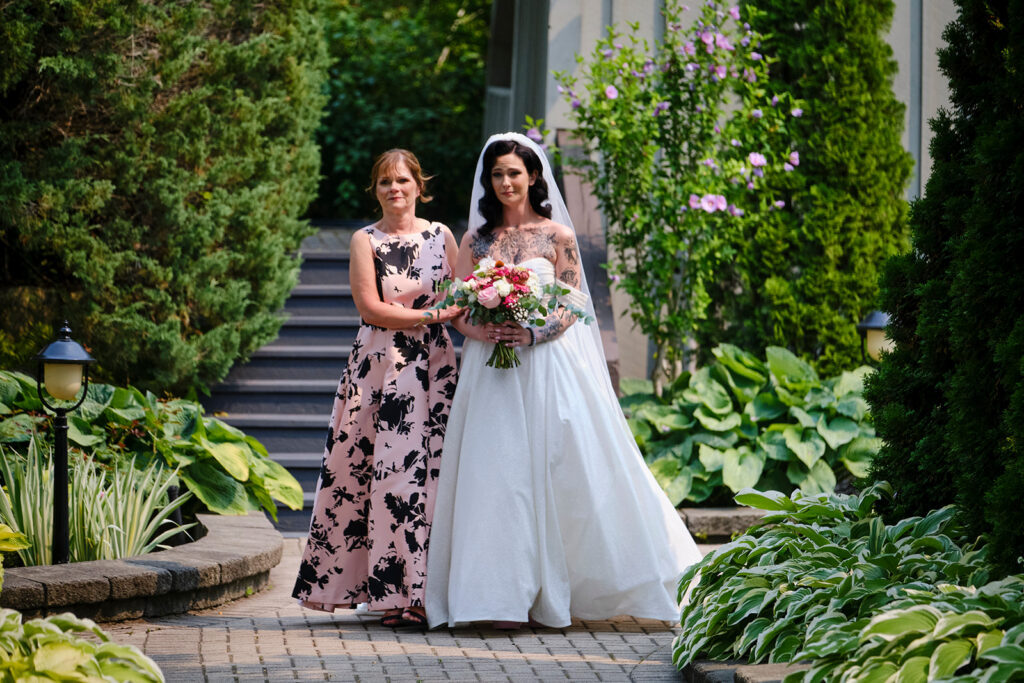 Mother of the bride and the bride entering the ceremony of a summer wedding at Nottawasaga Inn Resort & Conference Centre during their wedding day in Alliston, Ontario.